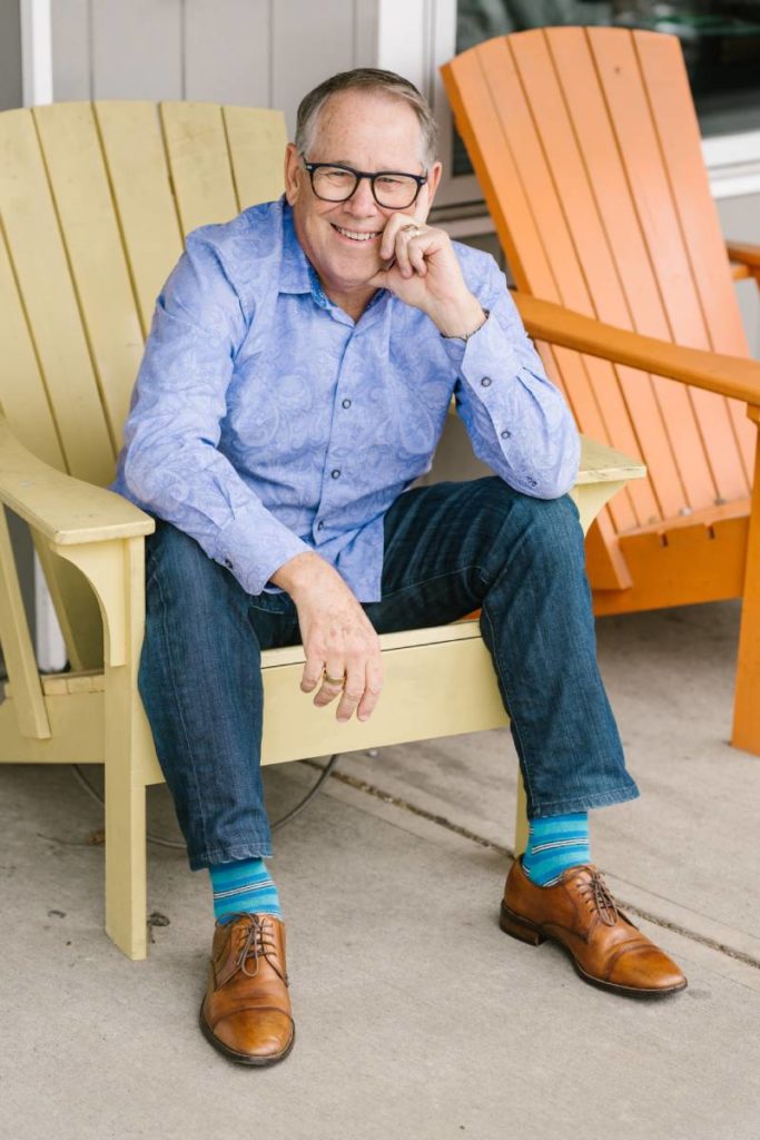 Speaker and best selling author of UnCommon Leadership®, Ed Chaffin, sitting in chair holding documents